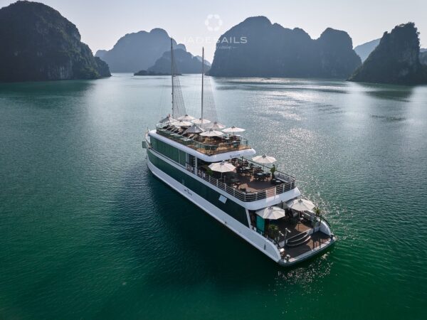 JadeSails luxury cruise ship with modern white design sailing through the limestone islands of Lan Ha Bay.